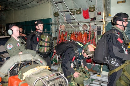 Pararescuemen from the 129th Rescue Wing of the California Air National Guard prepare to jump from the rear door of a Coast Guard C-130 Hercules airplane about 1,400 miles southwest of San Diego, Calif., April 1, 2010. The Coast Guard and Air National Guard worked together to respond to medevac an injured 57-year-old man by dropping four pararescuemen, an inflatable boat and other rescue and survival equipment.