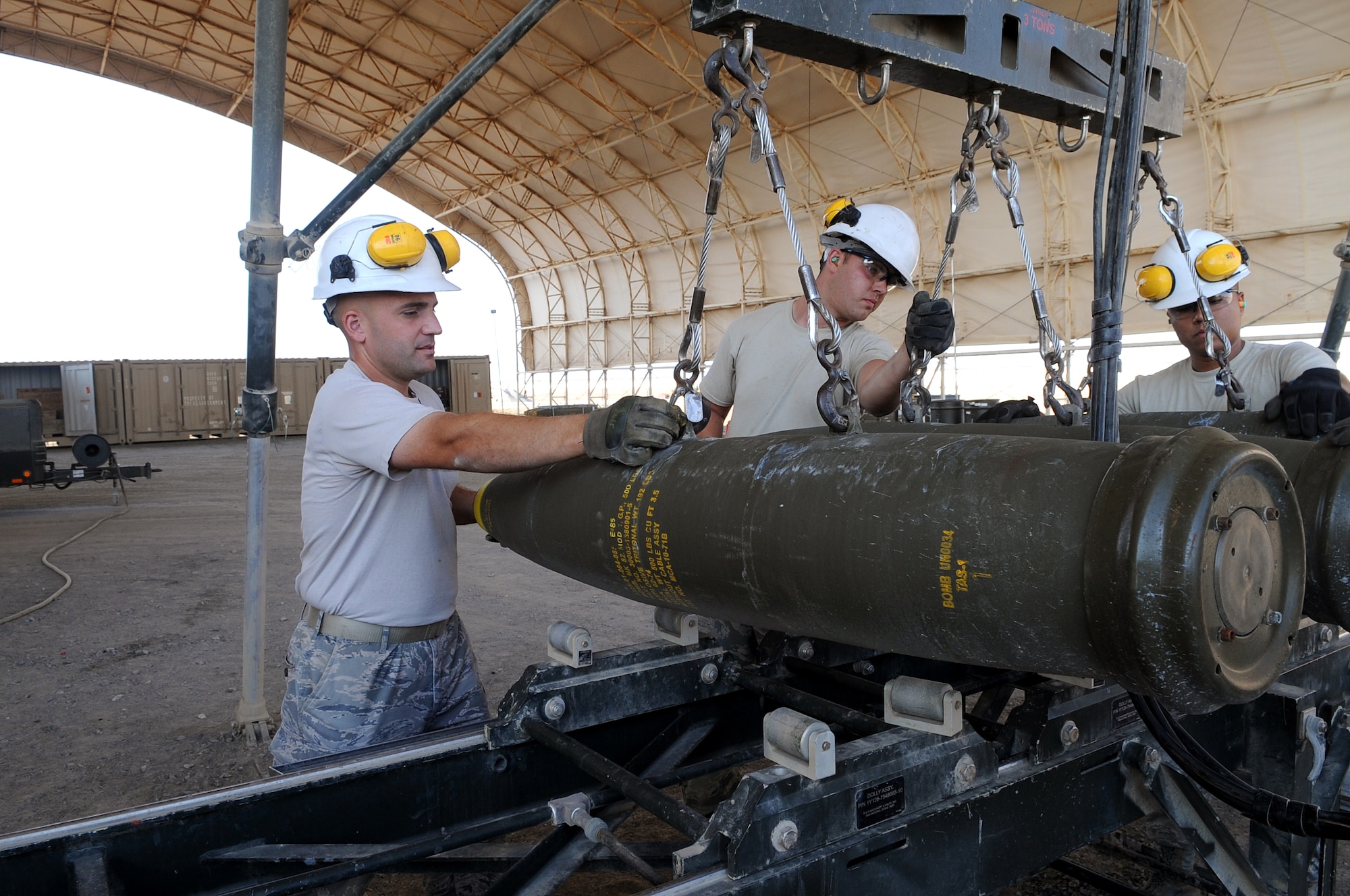 From left, Tech. Sgt. Stephen, shift lead, Senior Airman Adam and Airman 1st Class Luis, both munitions crew chief, load MK-82s onto a rail assembly Dec. 21, 2014, in Southwest Asia.  The Airmen are preparing to assemble 24 GBU-38s in preparation for real-world combat sorties.  Stephen is deployed from Joint Base Elmendorf-Richardson, Alaska, and Adam and Luis are deployed from Seymour Johnson Air Force Base, N.C.  (U.S. Air Force photo/Senior Master Sgt. Carrie Hinson)