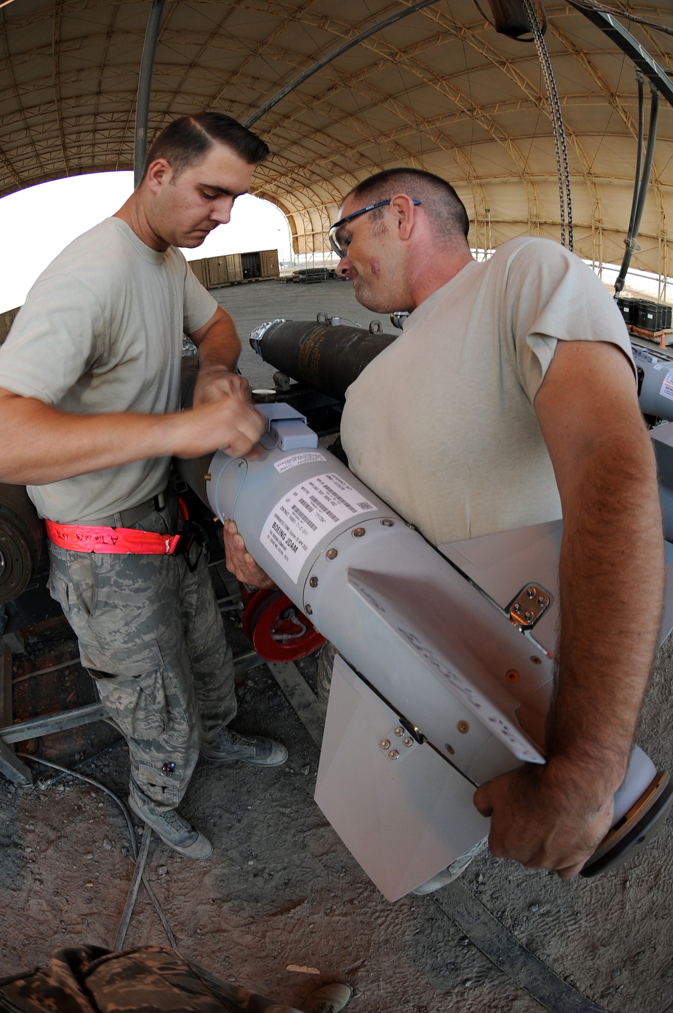Master Sgt. Adam, right, and Senior Airman Adam, both Ammo troops, work together to install a KMU-572 fin onto an MK-82 munition Dec. 21, 2014, in Southwest Asia.  The Airmen are part of a seven-man team building 24 GBU-38s in support of Operation INHERENT RESOLVE.  Both Airmen are deployed from Seymour Johnson Air Force Base, N.C.  (U.S. Air Force photo/Senior Master Sgt. Carrie Hinson)