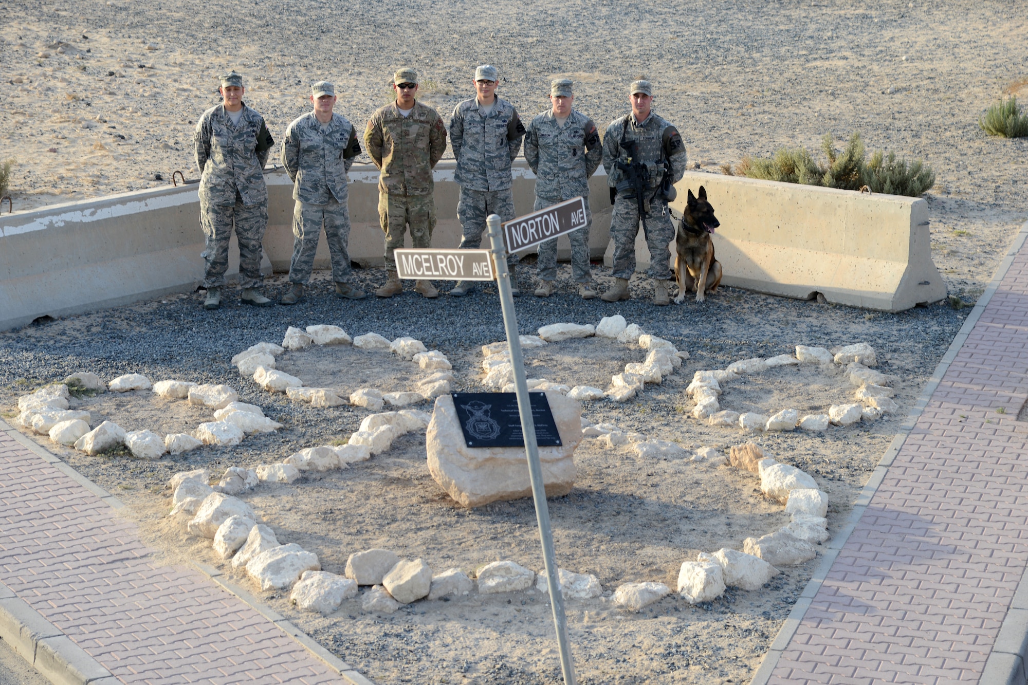 SOUTHWEST ASIA - Airmen from the 386th Expeditionary Security Forces Squadron stand behind the rebuilt Security Forces K9 memorial here Dec. 28, 2014. The original memorial, dedicated to Tech. Sgt. Jason L. Norton and Staff Sgt. Brian McElroy, was damaged in a vehicle accident in September. (U.S. Air Force photo by Tech. Sgt. Jared Marquis/released)