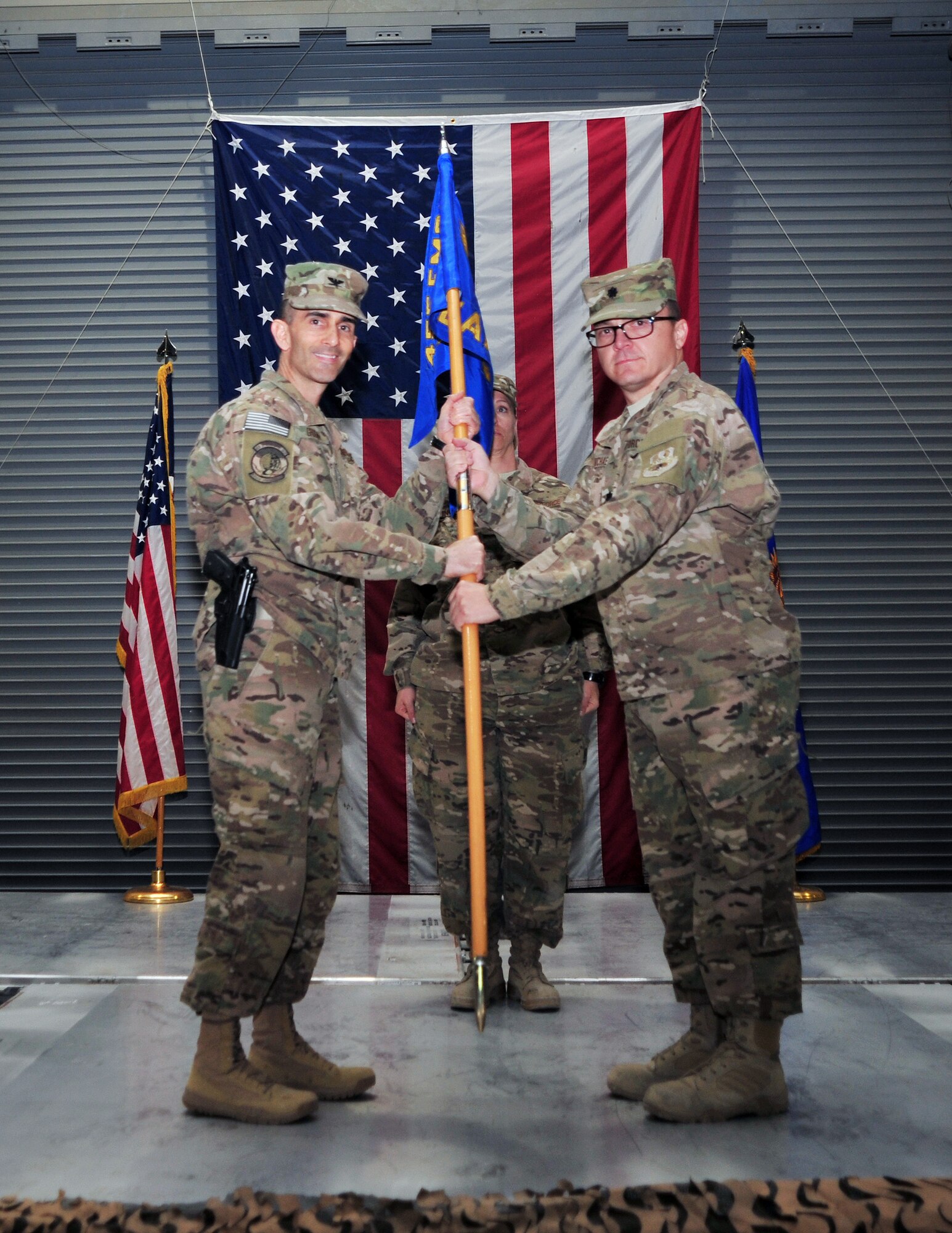 U.S. Air Force Lt. Col. Christopher Carmichael, 455th Expeditionary Aerial Port Squadron commander, hands the 455 EAPS guidon to U.S. Air Force Col. Michael Grogan, 455th Expeditionary Mission Support Group commander, during a squadron inactivation ceremony Jan. 1 at Bagram Airfield, Afghanistan. The squadron, now belonging to the 455th Expeditionary Logistics Readiness Squadron, will henceforth be recognized as an aerial port flight. (U.S. Air Force photo by Staff Sgt. Whitney Amstutz/released)