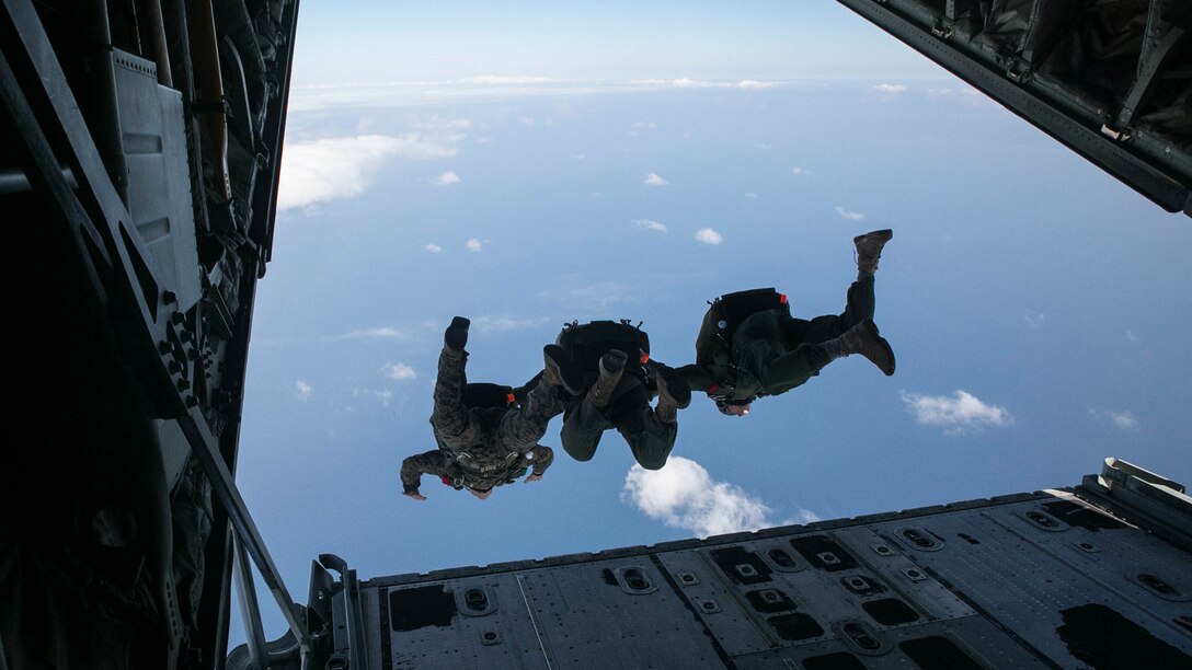 Gunnery Sgt. Gabriel Machado, left, Master Sgt. Raul Argumedo, center, and Gunnery Sgt. Matthew Bateman jump in tandem from a KC-130J Super Hercules aircraft Nov. 20, 2014 over Ie Shima Training Facility, off the northwest coast of Okinawa, Japan. The Marines jumped from an altitude of 10,000 feet during the high speed training. Machado, from New York, New York, is an air delivery specialist with 3rd Reconnaissance Battalion, 3rd Marine Division, III Marine Expeditionary Force. Argumedo, from Los Angeles, California, is an air delivery specialist with the battalion. Bateman, from Gaithersburg, Maryland, is a reconnaissance man with the battalion. 