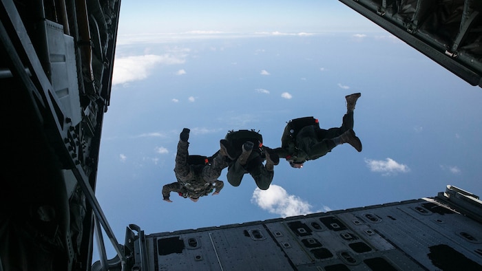 Gunnery Sgt. Gabriel Machado, left, Master Sgt. Raul Argumedo, center, and Gunnery Sgt. Matthew Bateman jump in tandem from a KC-130J Super Hercules aircraft Nov. 20, 2014 over Ie Shima Training Facility, off the northwest coast of Okinawa, Japan. The Marines jumped from an altitude of 10,000 feet during the high speed training. Machado, from New York, New York, is an air delivery specialist with 3rd Reconnaissance Battalion, 3rd Marine Division, III Marine Expeditionary Force. Argumedo, from Los Angeles, California, is an air delivery specialist with the battalion. Bateman, from Gaithersburg, Maryland, is a reconnaissance man with the battalion. 