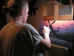 Louisiana National Guardsman 1st Lt. Heather S. Englehart, the executive officer for the 1021st Vertical Engineer Company, 205th Engineer Battalion, 225th Engineer Brigade, paints a portrait of her military experiences at her home in New Orleans. Englehart was featured on the CBS
Sunday Morning News last December as a result of the paintings she created
while deployed to Iraq with the 1st Battalion, 244th Aviation Regiment, in
2004-2005.