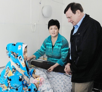 Chaplain (Lt. Col.) James Kinsey, the 376th Air Expeditionary Wing head chaplain, who is also a member of the 129th Rescue Wing of the California Air National Guard, speaks to Firuza Nurahunova as her mother, Polak, looks on. Firuza, a 13-year-old Kyrgyz girl, just had open heart surgery to repair a faulty valve at a hospital in Bishkek, Kyrgyzstan, March 21, 2010. This is Firuza's third heart surgery, and it was funded by Airmen in the Manas Area Benefits Outreach Society at the transit center.