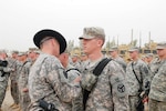 Col. Jeff H. Holmes, the commander of the 278th Armored Cavalry Regiment of the Tennessee National Guard, places the combat patch on his son, Spc. Hulon Holmes, a gunner with 3rd Platoon, F Troop, 2nd Squadron, 278th ACR, during a ceremony at Joint Base Balad, Iraq, April 8, 2010.