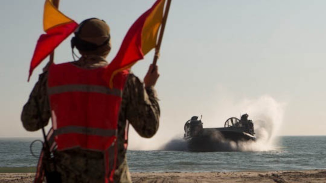 Marines with Combat Logistics Battalion 2, Combat Logistics Regiment 2, 2nd Marine Logistics Group, work with the Marines and sailors of the 24th Marine Expeditionary Unit as they guide a Navy landing craft air cushion onto Onslow Beach aboard Camp Lejeune, N.C., Dec. 16, 2014. Marines loaded vehicles, personnel and ammunition aboard the LCACs to be transported to the USS Fort McHenry. 