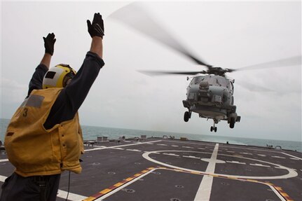 JAVA SEA (Jan. 3, 2015) - U.S. Navy Petty Officer 2nd Class Adam Garnett signals an MH-60R Sea Hawk helicopter from Helicopter Maritime Strike Squadron 35 on the flight deck of the littoral combat ship USS Fort Worth. Fort Worth is currently in the Java Sea conducting helicopter search-and-recovery operations with the USS Sampson as part of Indonesian-led efforts to locate downed AirAsia Flight 8501. 