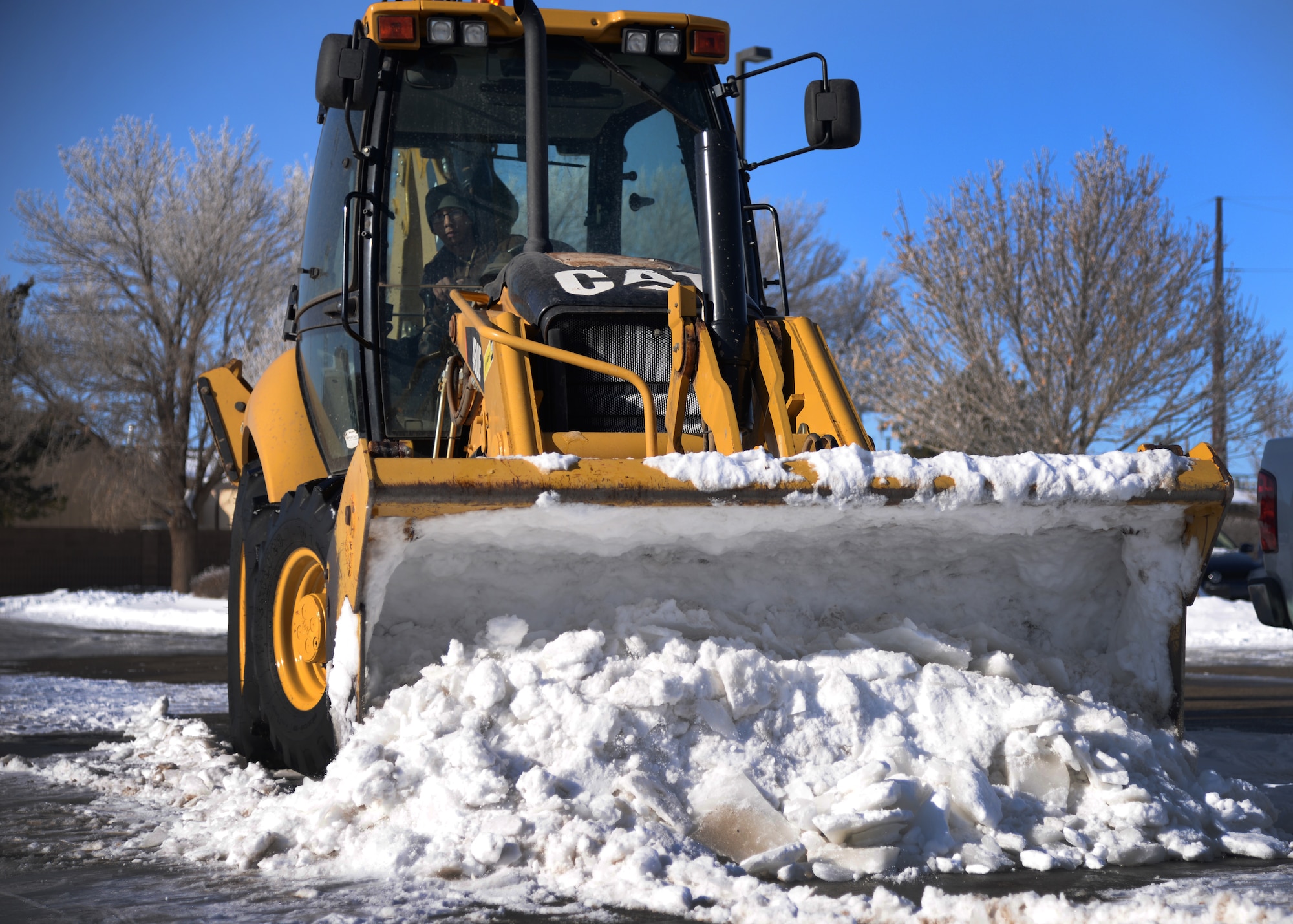 A U.S. Air Force Air Commando clears a parking lot for base defenders Jan. 5, 2015 at Cannon Air Force Base, N.M. The top priority for the pavement and construction equipment team has been clearing the airfield to enable flying operations; base roads and facilities are next on their list so our personnel and families can safely maneuver on the installation. (U.S. Air Force photo/Staff Sgt. Alexxis Mercer)