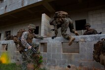 U.S. Marines with Company E, Battalion Landing Team 2nd Battalion, 4th Marines, (BLT) 31st Marine Expeditionary Unit, jump over a wall while conducting a vertical assault at Combat Town, Okinawa, Japan, Dec. 8, 2014. Company E is conducting training as part of the MEU Exercise and pre-deployment training. (U.S. Marine Corps Photo by Lance Cpl. Richard Currier/ Released)