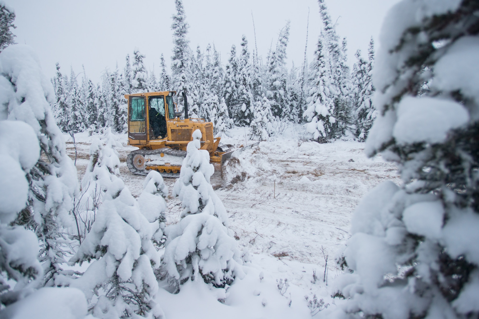 U.S. Air Force Senior Airman Zach Harter , a heavy equipment operator assigned to the 354th Civil Engineer Squadron, uses a bulldozer to build an ice bridge in Fairbanks, Alaska, Dec. 2, 2014. The bridge must be constructed every other year to provide access to the $20 million range complex used to train pilots from around the world during RED FLAG-Alaska exercises.  (U.S. Air Force photo by Tech. Sgt. Joseph Swafford/Released)
