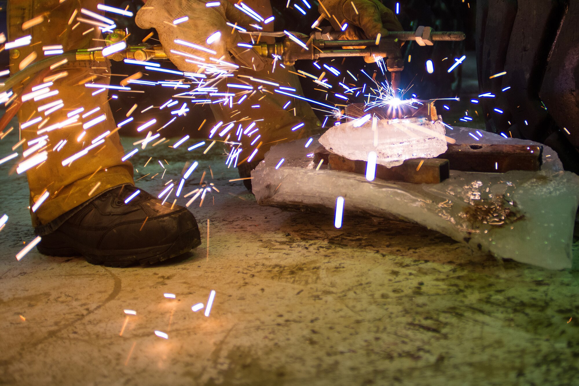 U.S. Air Force Senior Airman Tyler Dray, a range maintenance structures journeyman assigned to the 354th Civil Engineer Squadron, uses a torch to prep materials to construct an ice bridge Dec. 2, 2014, at Eielson Air Force Base, Alaska. The bridge must be constructed every other year to provide access to the $20 million range complex used to train pilots from around the world during RED FLAG-Alaska exercises.  (U.S. Air Force photo by Tech. Sgt. Joseph Swafford/Released)
