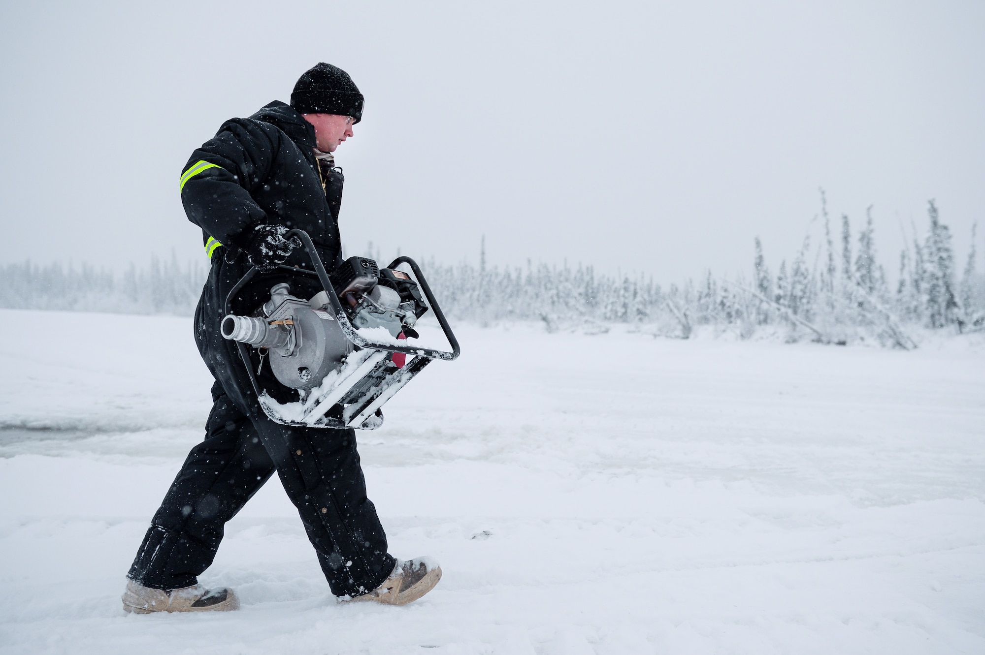 U.S. Air Force Senior Airman John Lee, a range maintenance structures journeyman assigned to the 354th Civil Engineer Squadron, carries a water pump across an ice bridge in Fairbanks, Alaska, Dec. 2, 2014. The bridge must be constructed every other year to provide access to the $20 million range complex used to train pilots from around the world during RED FLAG-Alaska exercises.  (U.S. Air Force photo by Staff Sgt. Shawn Nickel/Released)
