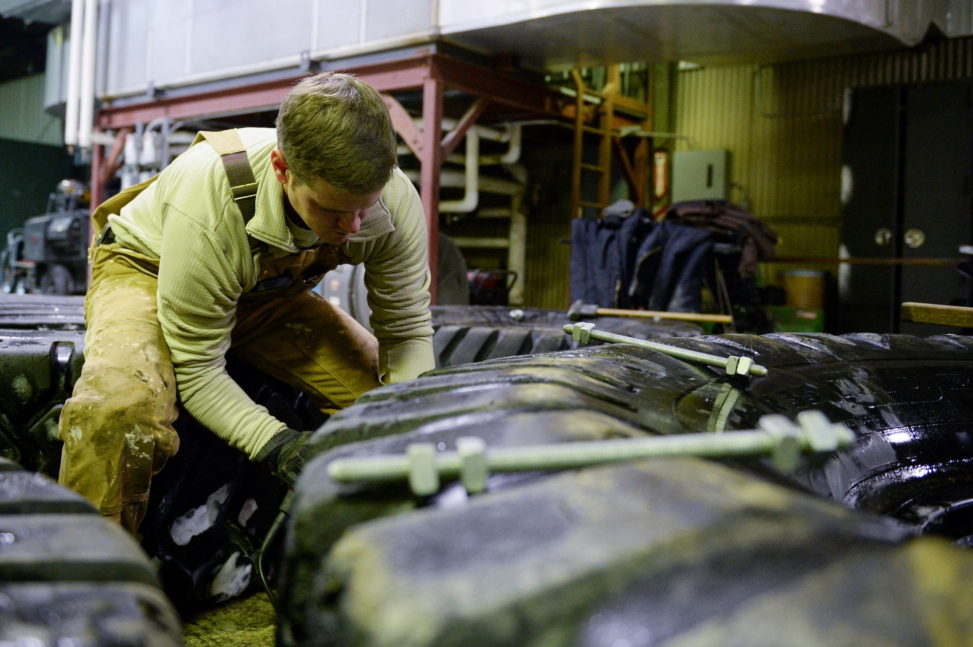 U.S. Air Force Senior Airman John Lee, a range maintenance structures journeyman assigned to the 354th Civil Engineer Squadron, preps a tire to be used to smooth out the service of an ice bridge Dec. 2, 2014, at Eielson Air Force Base, Alaska. The bridge must be constructed every other year to provide access to the $20 million range complex used to train pilots from around the world during RED FLAG-Alaska exercises.  (U.S. Air Force photo by Staff Sgt. Shawn Nickel/Released)
