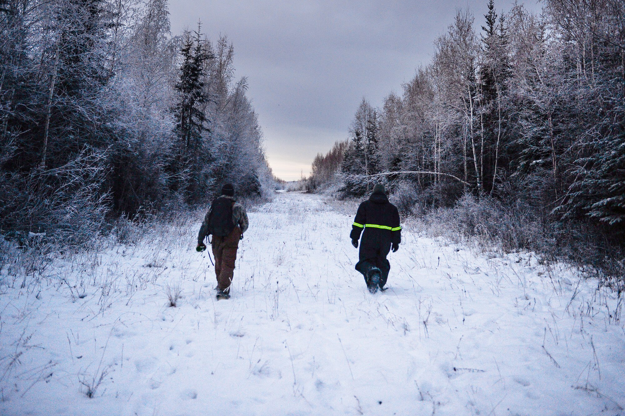 U.S. Air Force Senior Airman Tyler Dray, a range maintenance structures journeyman, and Senior Airman Jerry Mitchell, a heavy equipment operator, both assigned to the 354th Civil Engineer Squadron, walk to the site of an ice bridge in Fairbanks, Alaska, Nov. 20, 2014. The bridge must be constructed every other year to provide access to the $20 million range complex used to train pilots from around the world during RED FLAG-Alaska exercises.  (U.S. Air Force photo by Staff Sgt. Shawn Nickel/Released)
