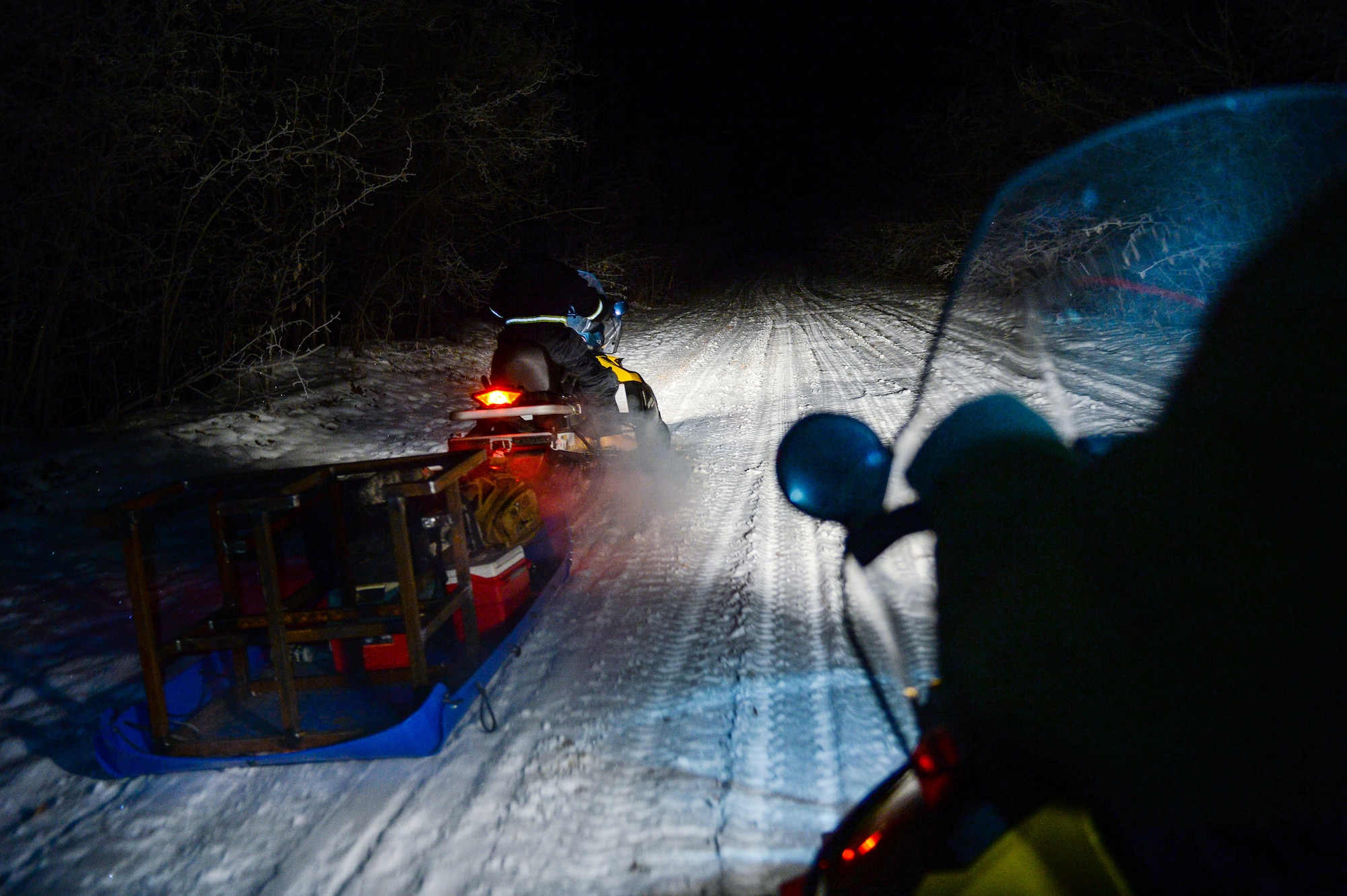 U.S. Airmen assigned to the 354th Civil Engineer Squadron ride snow machines to the site of an ice bridge in Fairbanks, Alaska, Nov. 20, 2014. The bridge must be constructed every other year to provide access to the $20 million range complex used to train pilots from around the world during RED FLAG-Alaska exercises.  (U.S. Air Force photo by Staff Sgt. Shawn Nickel/Released)
