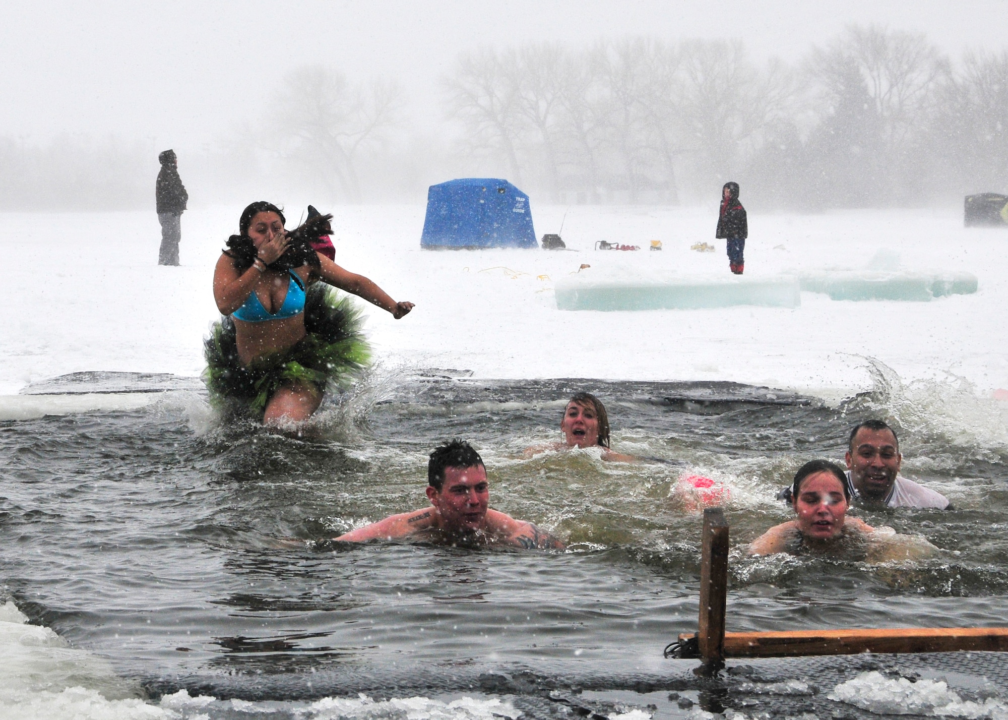 Staff Sgt. Andrea Rasmussen, 90th Civil Engineer Squadron explosive ordnance technician, jumps into the icy waters of Sloans Lake, Cheyenne, Wyo., as her team swims out Jan. 3, 2014. Rasmussen and her team participated in the third annual Schwartz Memorial Plunge in honor of Tech. Sgt. Matthew Schwartz, a 90th CES explosive ordnance technician who was killed in action while deployed to Afghanistan Jan. 5, 2012.(U.S. Air Force Photo/Lan Kim)

