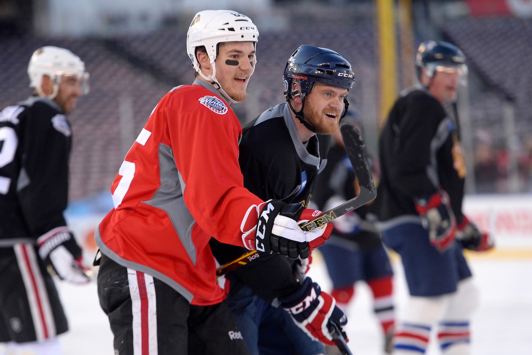 Chicago Blackhawks center Andrew Shaw, left, and Jeremy Mishler of the USA Warriors wounded veterans hockey team react to checking each other during a media day game for the Winter Classic 2015 in Washington, D.C., Dec. 31, 2014. The two teams played pickup game style hockey for about 15 minutes on the outdoor ice at Nationals Stadium.