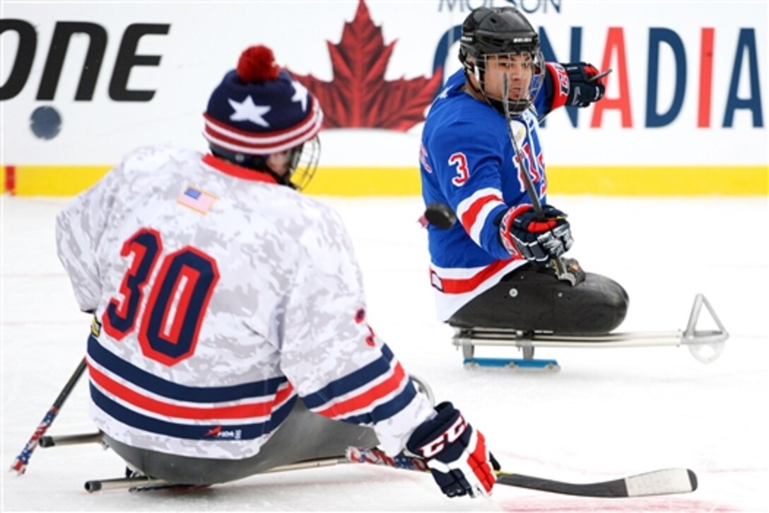 USA Warriors sled hockey team player Ralph DeQuebec flips a puck past a teammate while playing on the National Hockey League’s Winter Classic 2015 outdoor ice at Nationals Park in Washington, D.C., Jan 2, 2015.