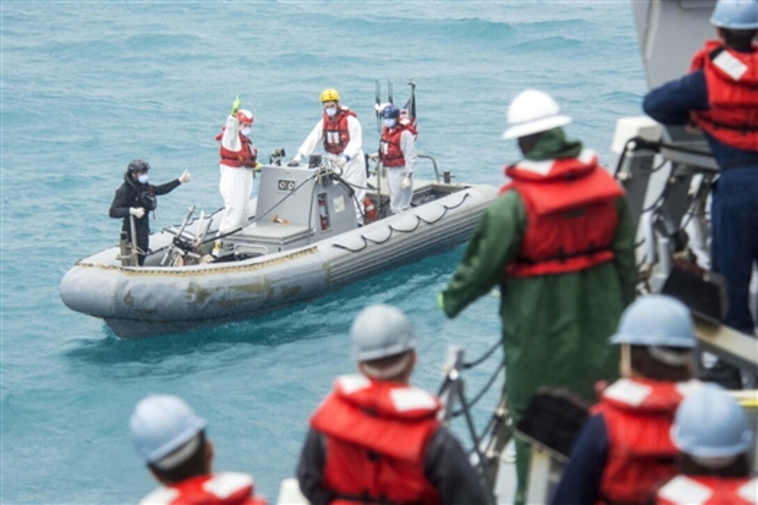 The recovery team assigned to the destroyer USS Sampson signals the boat crew as they support the Indonesian-led search efforts for Air Asia Flight 8501 in the Java Sea, Jan. 4, 2015.