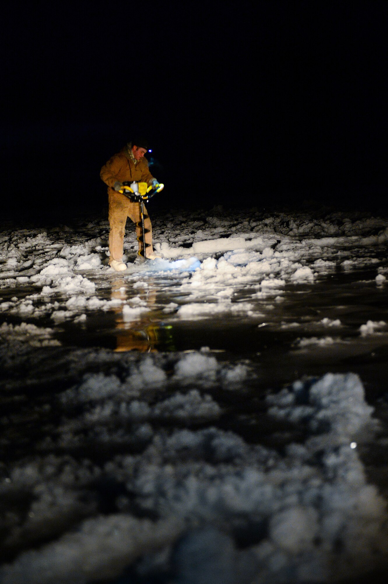 Senior Airman Tyler Dray uses an ice auger while constructing an ice bridge in Fairbanks, Alaska, Nov. 20, 2014. The bridge must be constructed every other year to provide access to the $20 million range complex used to train pilots from around the world during Red Flag-Alaska exercises. Dray is a range maintenance structures journeyman assigned to the 354th Civil Engineer Squadron. (U.S. Air Force photo/Staff Sgt. Shawn Nickel) 