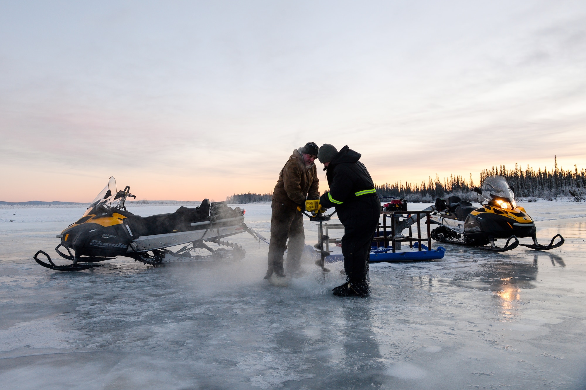Senior Airmen Tyler Dray and Jerry Mitchell use an ice auger Nov. 20, 2014, while constructing an ice bridge in Fairbanks, Alaska. The bridge must be constructed every other year to provide access to the $20 million range complex used to train pilots from around the world during Red Flag-Alaska exercises. Dray is a range maintenance structures journeyman and Mitchell is a heavy equipment operator with the 354th Civil Engineer Squadron on Eielson Air Force Base, Alaska. (U.S. Air Force photo/Staff Sgt. Shawn Nickel)