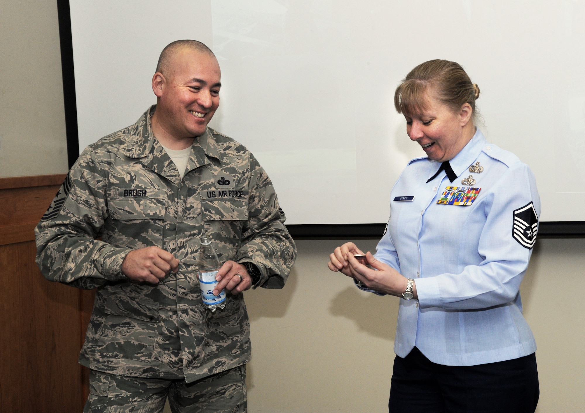 Chief Master Sgt. Mitchell O. Brush, Senior Enlisted Advisor for the National Guard Bureau, left, gives one of his coins to Master Sgt.  Anja O’Neil, assigned to the 123rd Fighter Squadron, right, during his visit to the Portland Air National Guard Base, Ore., Jan. 5, 2015. Chief Brush toured the air base and led a town hall event to highlight the changes and challenges that Soldiers and Airmen of the National Guard face going into the New Year. (U.S. Air National Guard photo by Tech. Sgt. John Hughel, 142nd Fighter Wing Public Affairs/Released)