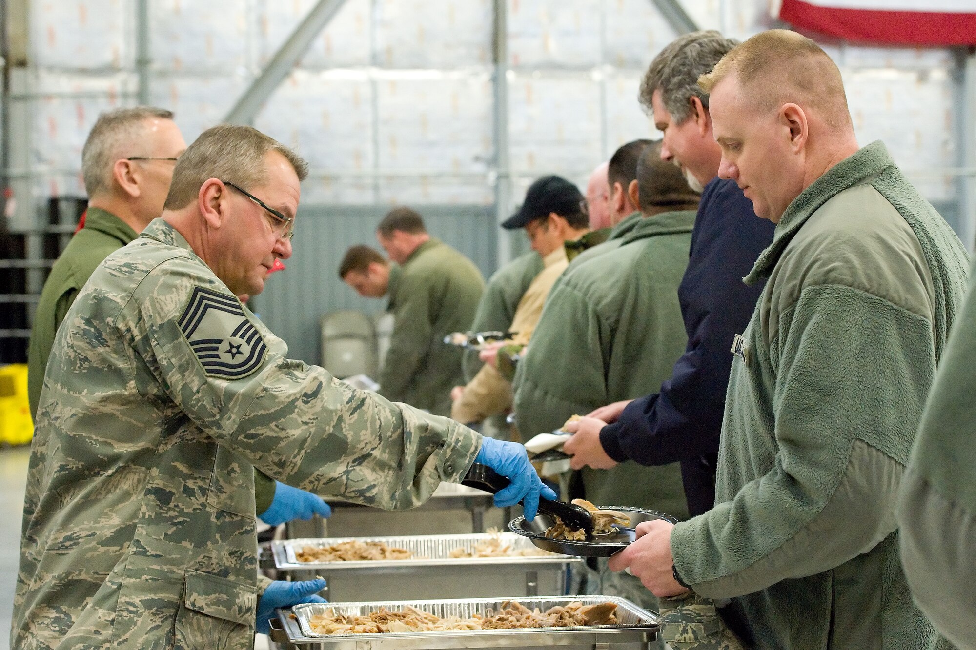 Chief Master Sgt. James Dowd, 512th Aircraft Maintenance Squadron, serves a Team Dover member during the 10th Annual "Feed the Troops" day shift dinner Dec. 23, 2014, in building 792 on Dover Air Force Base, Del. Thirty-eight turkeys were cooked at the Dover Downs kitchen and transported to the base for a day and night shift meal sittings. (U.S. Air Force photo/Roland Balik)