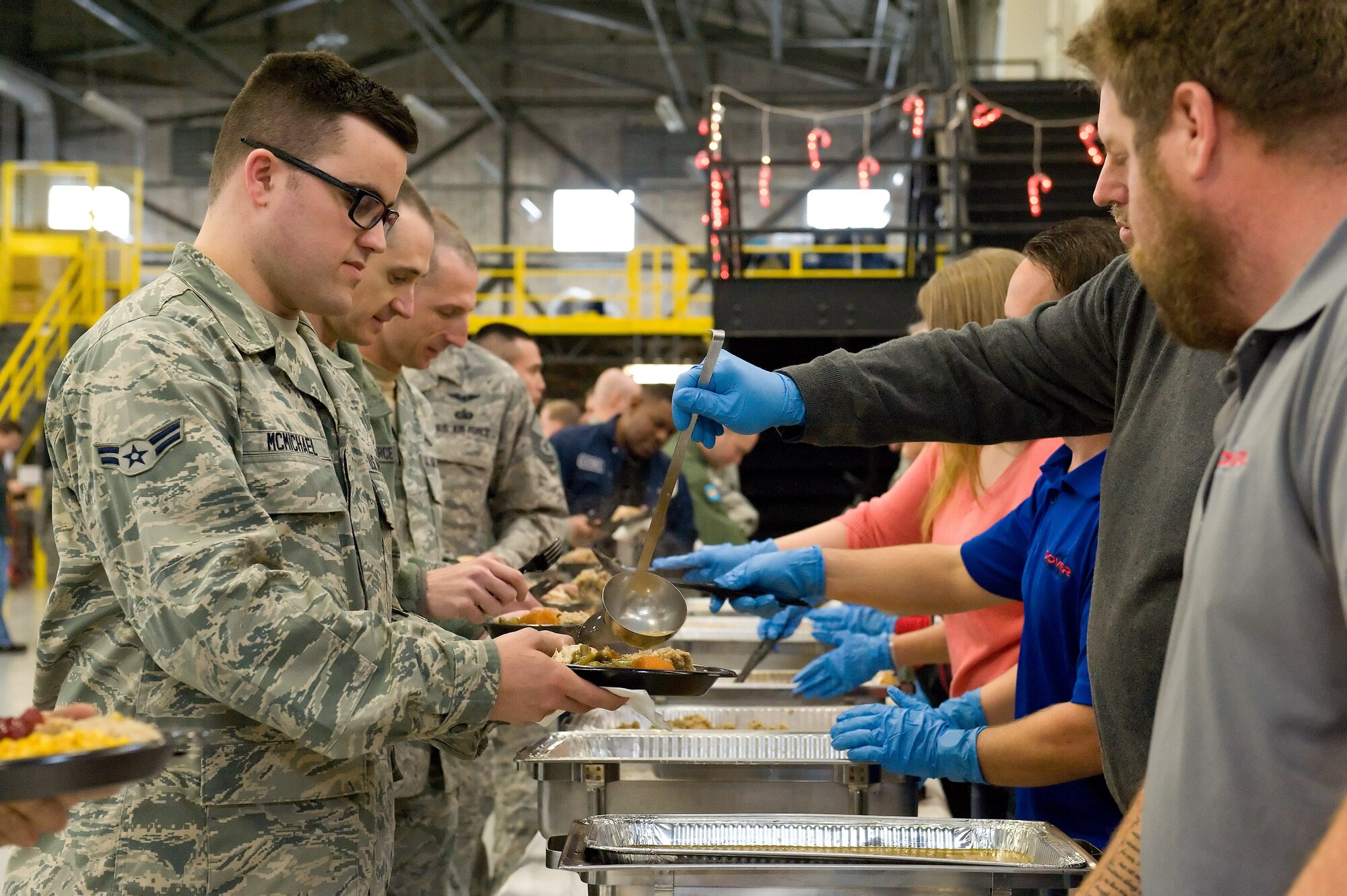 Airman 1st Class Jeffrey McMichael, 736th Aircraft Maintenance Squadron, goes through the serving line during the 10th Annual "Feed the Troops" day shift dinner Dec. 23, 2014, in building 792 on Dover Air Force Base, Del. Around 450 Team Dover members were served during the day shift meal, while another 125 were served during the night shift meal. (U.S. Air Force photo/Roland Balik)