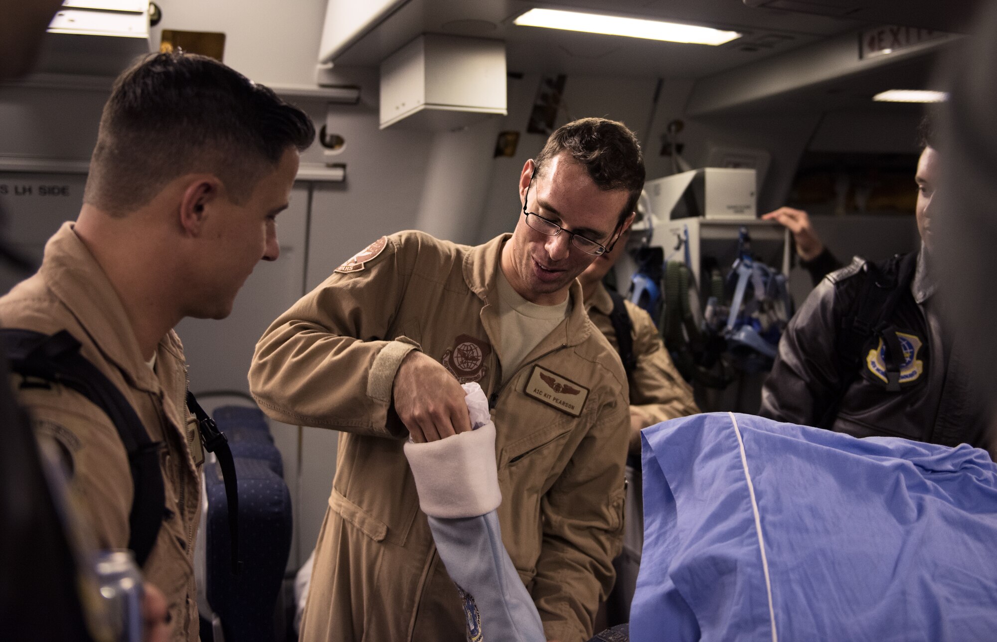 Airman 1st Class Kristoffer Pearson, 2nd Aerial Refueling Squadron boom operator, opens a gift from wing leaders upon his return from deployment New Year's Eve, on the flightline at Joint Base McGuire-Dix-Lakehurst. Airman Pearson was presented with senior airman stripes as the sole member of the 305th AMW selected for a below-the-zone promotion. (U.S. Air Force photo/Staff Sgt. Katherine Tereyama/Released)