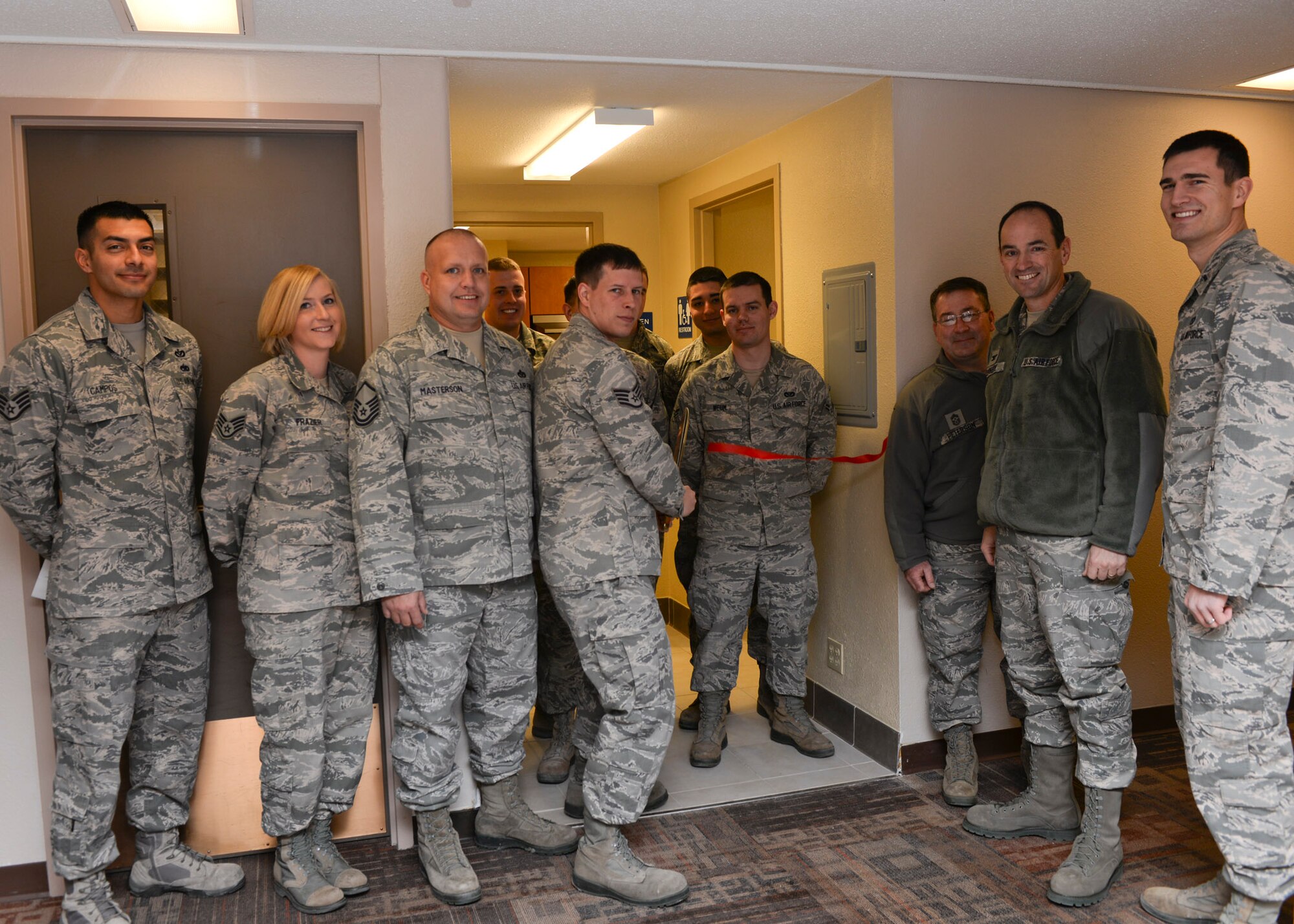 Staff Sgt. William Cochran, 28th Civil Engineer Squadron Airmen dormitory leader, cuts a ribbon recognizing the completion of the newly installed and renovated base dorm kitchenettes at Ellsworth Air Force Base, S.D., Dec. 22, 2014. The Rushmore and Borglum Dorm kitchens were updated as part of a 28th CES contingency construction project that saved more than $100,000 and required a team of 15 core members for completion. (U.S. Air Force photo by Senior Airman Anania Tekurio/Released)