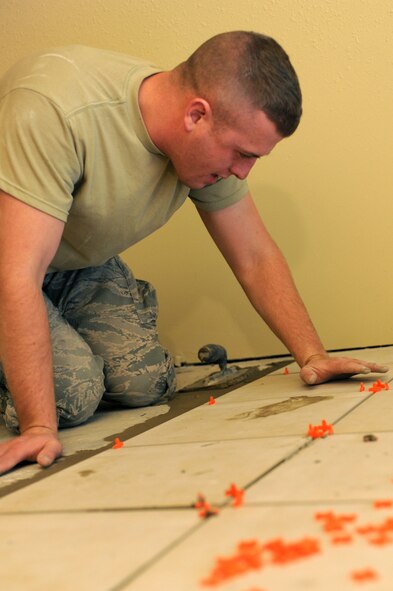 Staff Sgt. Kane Fulkerson, 28th Civil Engineer Squadron structural craftsman, lays tile during construction of a dormitory kitchenette at Ellsworth Air Force Base, S.D., Dec. 10, 2014. The kitchenette reopened Dec. 22, and gives dorm residents brand new unisex restrooms, two new stove and oven combos, a refrigerator and freezer unit, microwave, dishwasher, cabinets and plenty of counter space for Airmen to utilize and cook their meals. (U.S. Air Force photo by Senior Airman Hailey R. Staker)