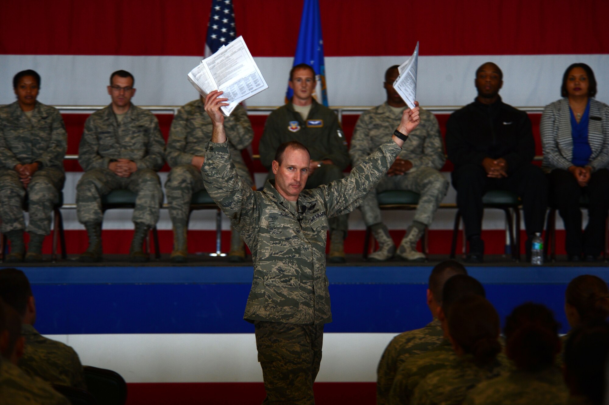 U.S. Air Force Col. Stephen Jost, 20th Fighter Wing commander, holds up Airmen Comprehensive Assessment forms during an all-call at Shaw Air Force Base, S.C., Jan. 6, 2015. Along with his new initiative “Airman Up”, Jost spoke about his enthusiasm for the new feedback forms that help supervisors get to know their Airmen better. (U.S. Air Force photo by Senior Airman Jensen Stidham/Released)