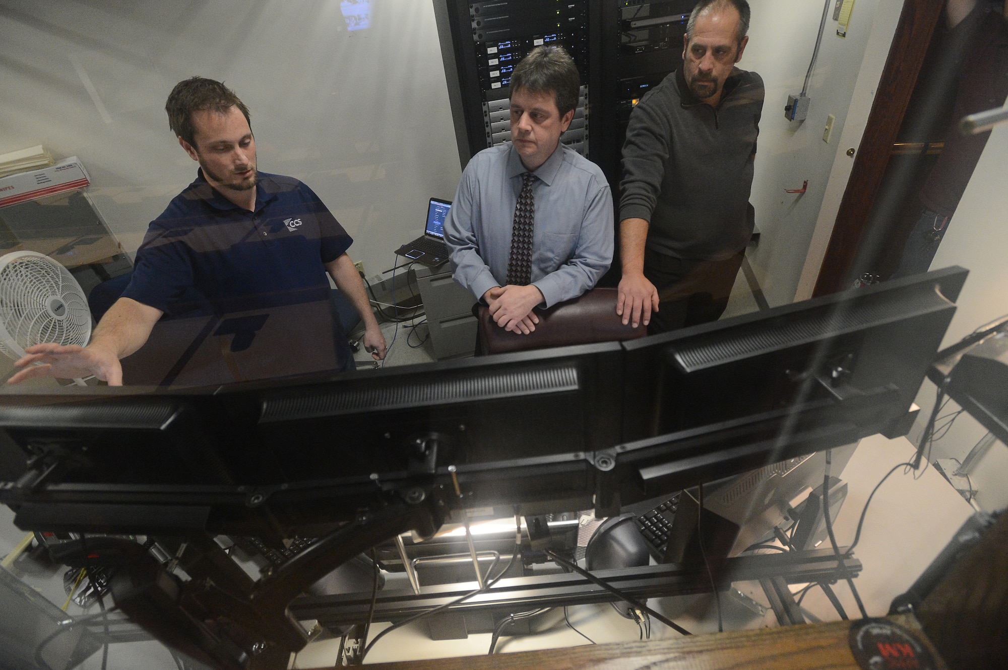 Brandon Meyers (left), lead project manager, CCS Presentation Systems, describes some of the various features of the audio visual system in the Hanscom Conference Center’s Lexington Amphitheater control center to Donn DeSilva (center), 66th Communications and Information Division information technology help desk specialist, and Patrick Libby, network engineer, communications division, during a training session at the conference center Dec. 30. The center’s two largest conference rooms, the Concord Room and Lexington Amphitheater, were recently upgraded to meet current industry standards. (U.S. Air Force photo by Jerry Saslav)