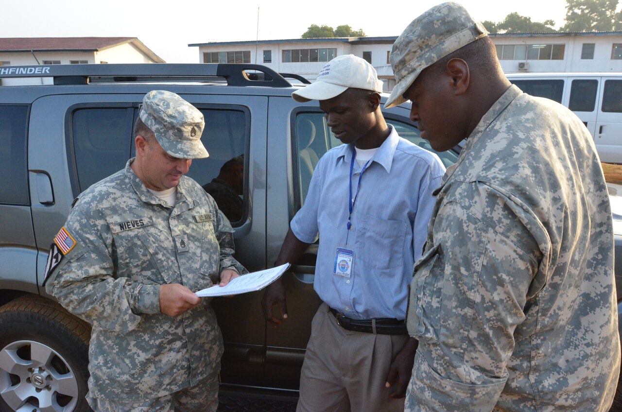 Army Staff Sgt. Jose Nieves, left, talks with Haji A. Sheriff, a vehicle driver supporting Operation United Assistance, about his routes before he goes out on a mission from the National Police Training Academy in Paynesville, Liberia, as Army Spc. Joshua Owens, right, listens, Dec. 27, 2014. Operation United Assistance provides logistics, training and engineering support to the U.S. Agency for International Development-led efforts to contain the Ebola virus outbreak in western Africa. U.S. Army photo by Sgt. Ange Desinor