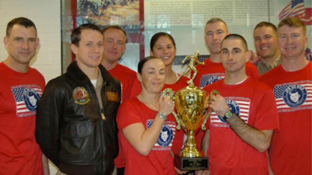 From the left, Col. Frank Donovan,  First Lt. Jonathan Messer, Maj. Brandon Turner, Maj. Michelle Macander, Maj. Jessica Ryu, Capt. Rob Sherwood, Capt. A.J. Cillo, Capt. Matt Windhol, and Maj. Jake Hood, Marines with the Expeditionary Warfare School, Quantico, Va., pose with the Kennedy Cup at the JFK 50 mile run in downtown Boonsboro, Maryland, Nov. 22, 2014. They won this year’s Kennedy Cup with completion times ranging from 7 hours, 22 minutes to just more than 11 hours, 30 minutes. The first JFK 50 Mile Challenge was held in the spring of 1963 and has since been held annually in Washington County, Maryland.