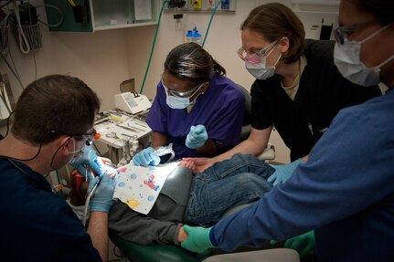 A dental technician comforts a child undergoing a dental procedure in Kotzebue, Alaska, April 15, 2010. An Air Force dental team composed of active duty, Guard and Reserve Airmen deployed to Kotzebue as part of Operation Arctic Care, a joint innovative readiness training exercise.