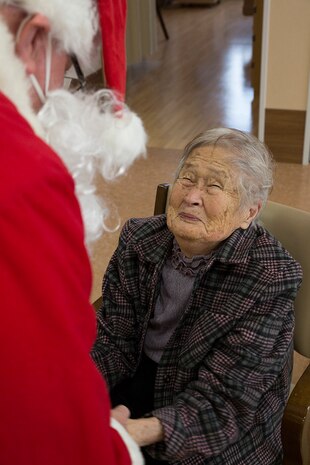 Retired Coast Guard Petty Officer 1st Class Elder Hal Pierce, a service missionary with the Church of Jesus Christ of Latter-day Saints, dressed as Santa, greets a resident of Nadamien Nursing Home in Iwakuni City, Japan, during a community relations event, Dec. 19, 2014. Volunteers from Marine Corps Air Station Iwakuni sang for and interacted with the residents. This event was made to build a stronger bond between the U.S. and Japan.