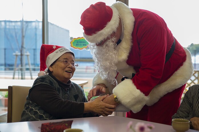 Retired Coast Guard Petty Officer 1st Class Elder Hal Pierce, a service missionary with the Church of Jesus Christ of Latter-day Saints, dressed as Santa, greets a resident of Nadamien Nursing Home in Iwakuni City, Japan, during a community relations event, Dec. 19, 2014. Volunteers from Marine Corps Air Station Iwakuni sang for and interacted with the residents. This event was made to build a stronger bond between the U.S. and Japan.