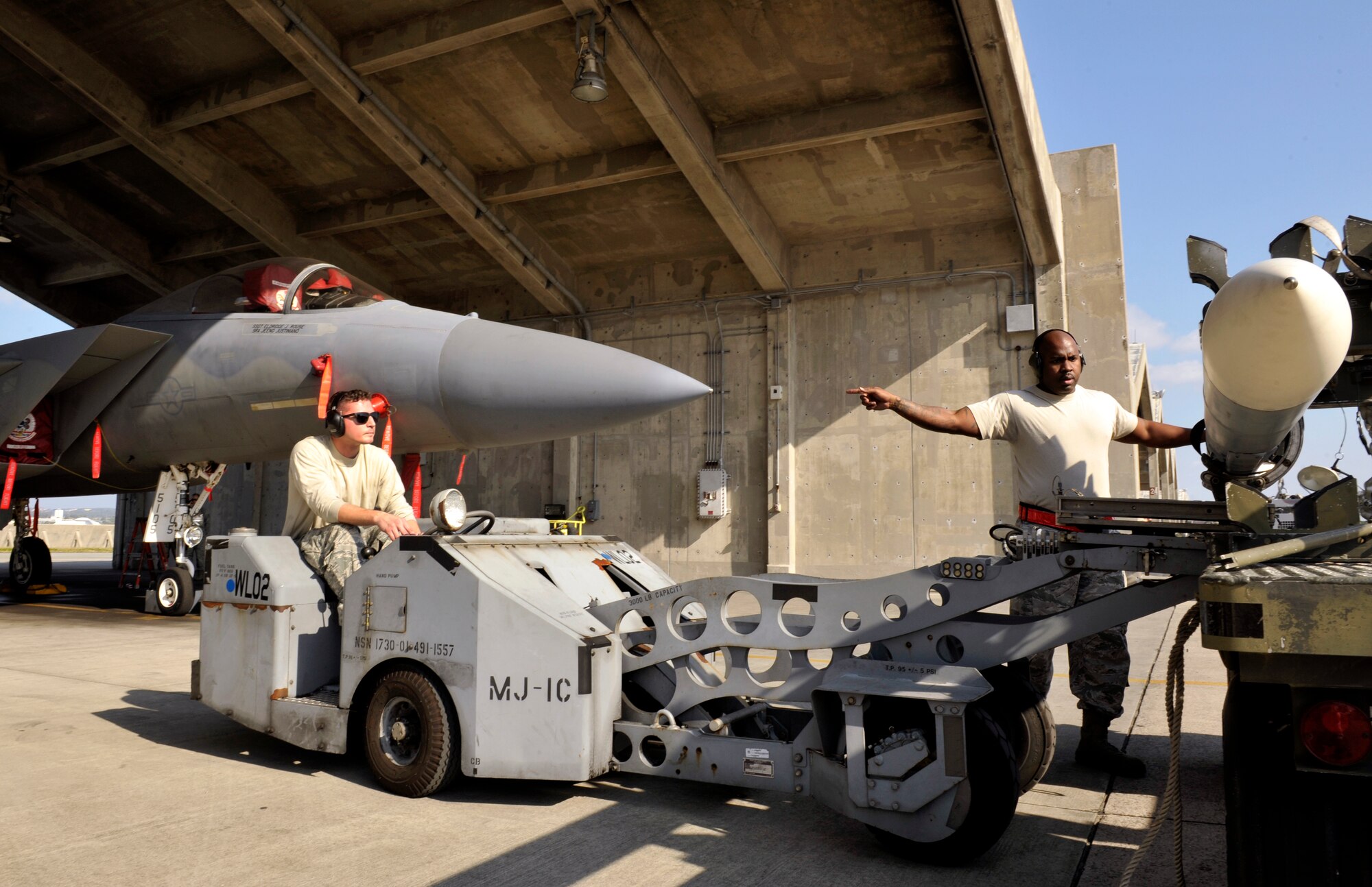 U.S. Air Force Staff Sgt. Jamar Hugie, 18th Aircraft Maintenance Squadron weapons load crew chief, guides an MJ-1C lift truck during a quarterly weapons load competition on Kadena Air Base, Japan, Jan. 5, 2015. The weapons load competition is a tradition held to raise morale, give airmen motivation to outperform their peers and set a higher standard for crews to come. (U.S. Air Force photo by Naoto Anazawa)