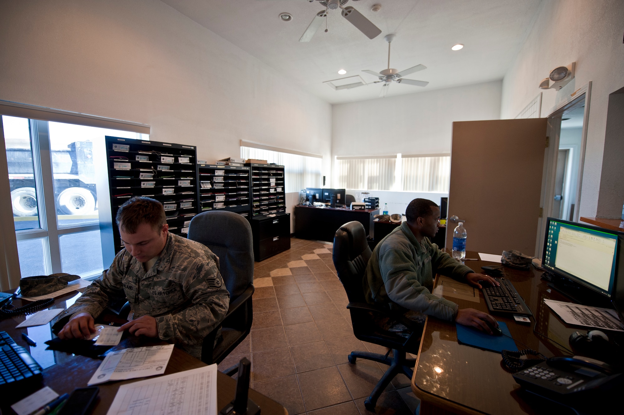 Staff Sgt. William Steenland, left, and Staff Sgt. Isaiah Brown, 99th Logistics Readiness Squadron vehicle dispatchers, process vehicle request forms at the vehicle operations center on Nellis Air Force Base, Nev., Jan. 6, 2015. Approximately 20 to 30 request forms are processed by dispatchers every day. (U.S. Air Force photo by Airman 1st Class Mikaley Towle)