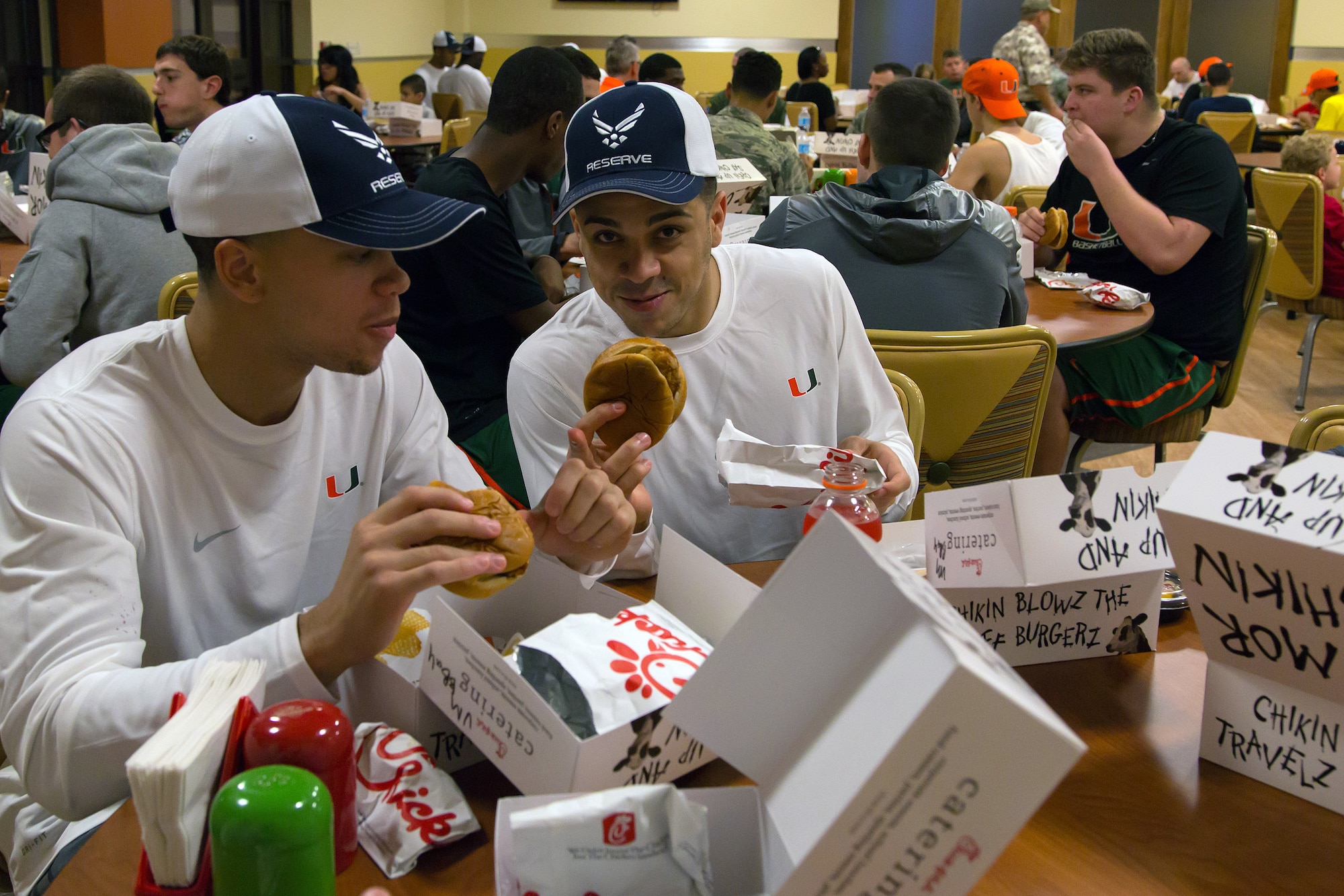 Two members of the University of Miami men’s basketball team enjoy dinner catered by Chick-Fil-A held at the Community Activity Center during the “Night out with the Hurricanes” event for military members and their families at Homestead Air Reserve Base, Fla., on Jan. 6. (Air Force photo/TSgt Lionel Castellano)