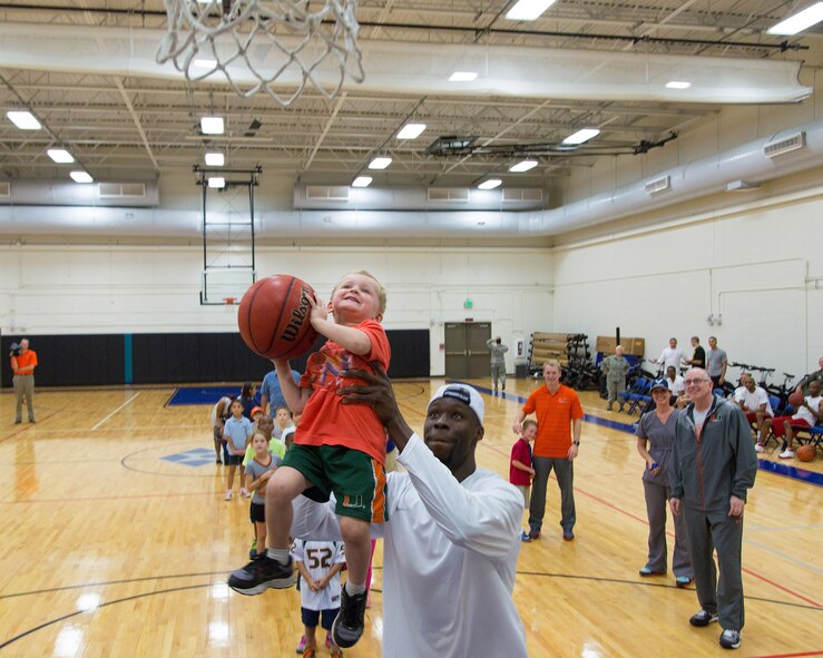 University of Miami men’s basketball player Tonye Jekiri prepares to assist one of the children in dunking the basketball during the “Night out with the Hurricanes” event for military members and their families at the Sam Johnson Fitness Center, Homestead Air Reserve Base, Fla., on Jan. 6 (Air Force photo/TSgt Lionel Castellano)