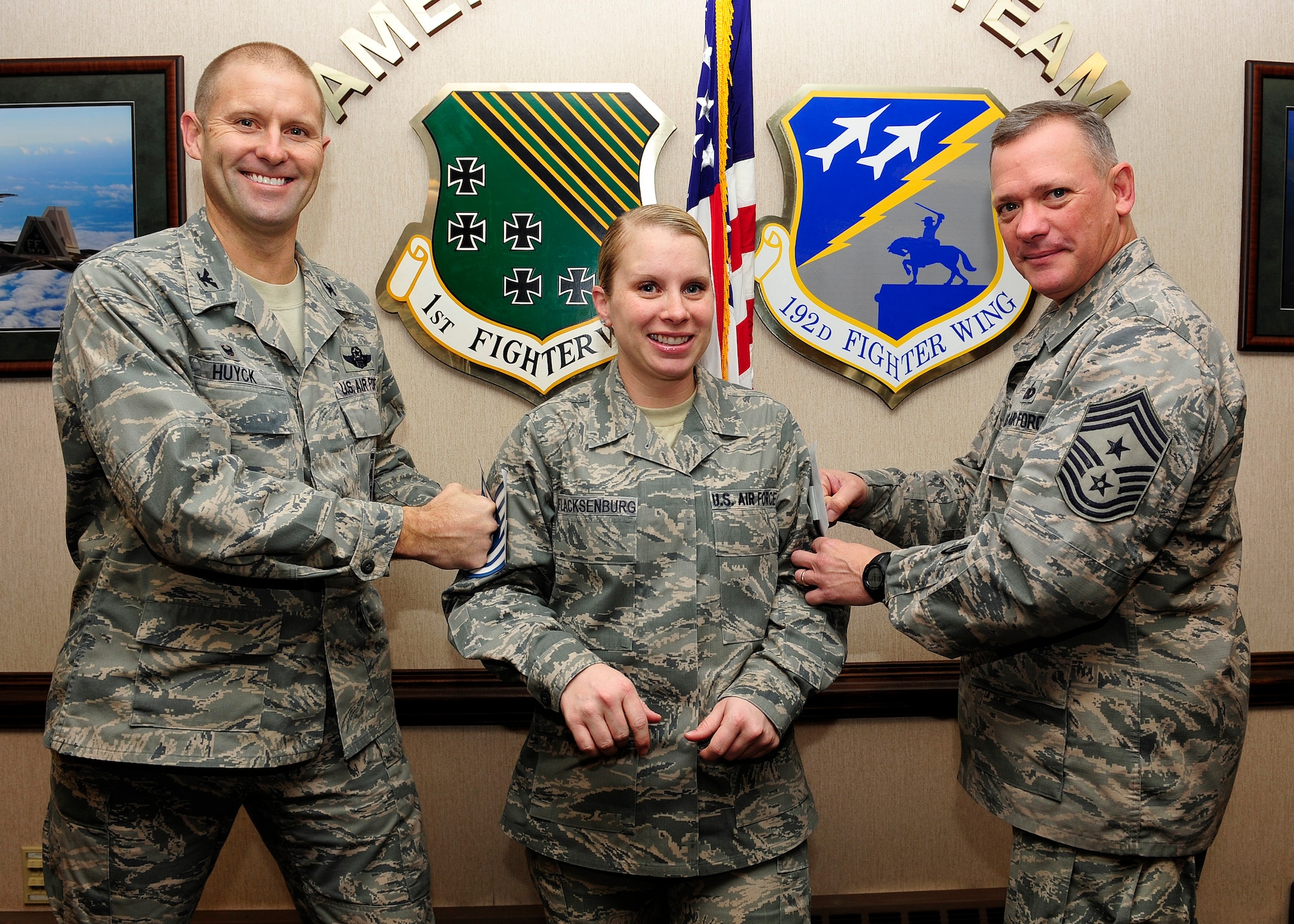 U.S. Air Force Col. Kevin Huyck, 1st Fighter Wing commander and Chief Master Sgt. Emmette Bush, 1st FW command chief, tack on Tech. Sgt. Niquoll Flacksenburg’s, 1st FW command section, technical sergeant stripes at Langley Air Force Base, Va., Jan. 6, 2015. Flacksenburg was promoted to technical sergeant through the Stripes for Exceptional Performers promotion. (U.S. Air Force photo by Airman 1st Class Breonna Veal/Released)