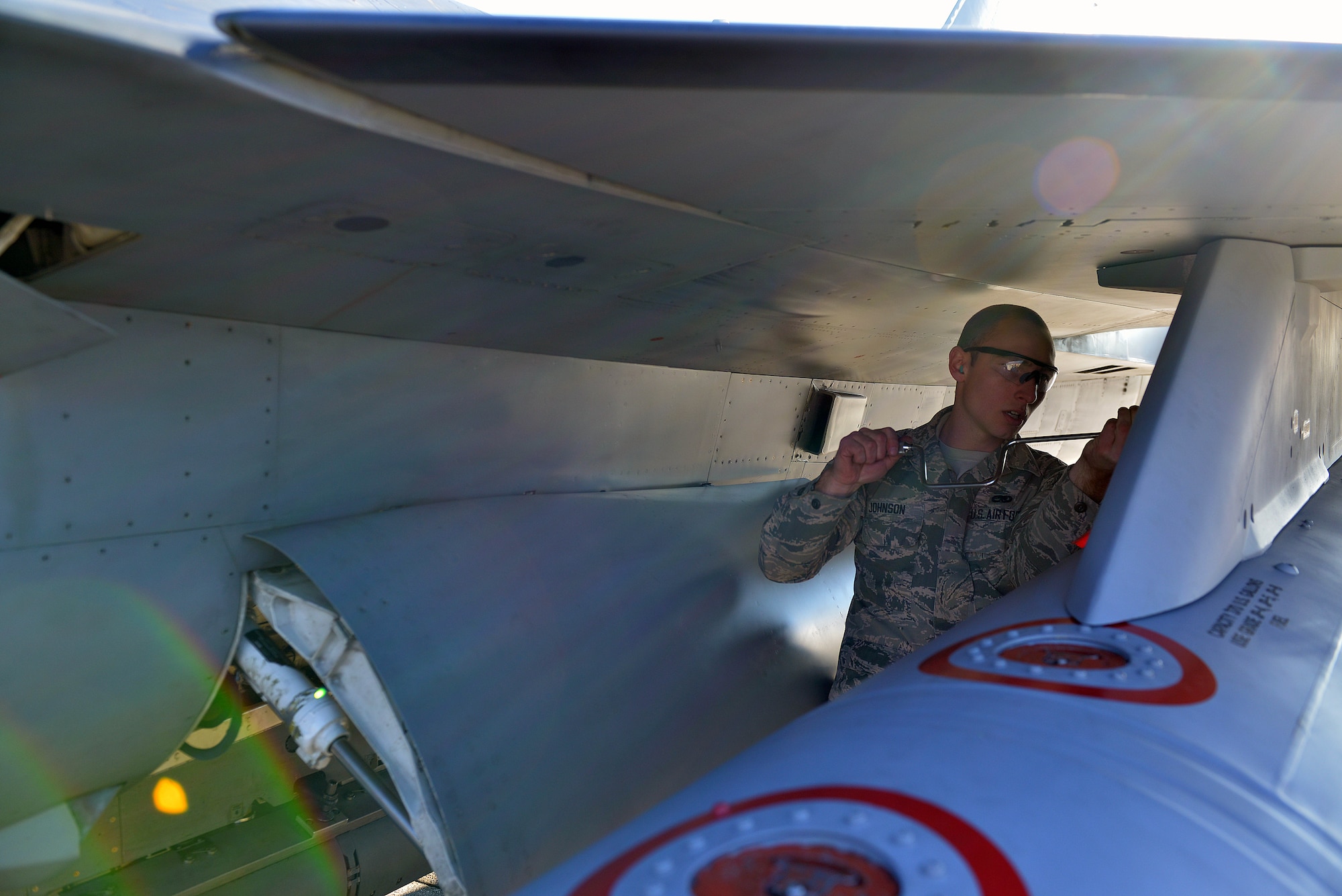 U.S. Air Force Airman 1st Class Thomas Johnson, 31st Aircraft Maintenance Squadron weapons load crew member, cranks a training munition into place on an F-16 Fighting Falcon wing, Jan. 6, 2015, at Aviano Air Base, Italy. The crews are graded on a written test, dress and appearance, their composite tool kit and their overall performance during the load competition. (U.S. Air Force photo/Airman 1st Class Ryan Conroy) 