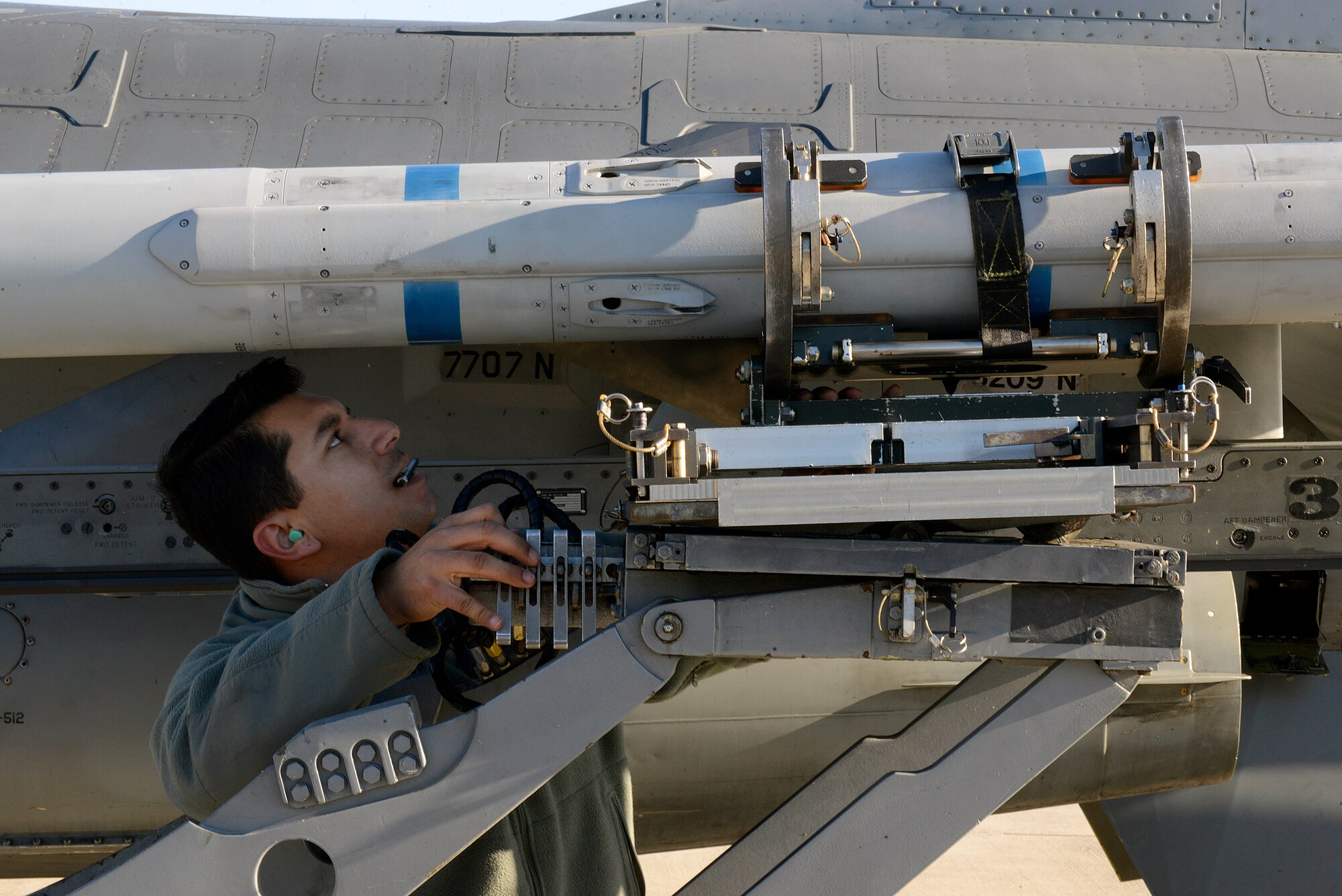 U.S. Air Force Staff Sgt. Sergio Flores, 31st Aircraft Maintenance Squadron weapons load crew team chief, helps guide a training munition onto the wing of an F-16 Fighting Falcon during a quarterly weapons load competition, Jan. 6, 2015, at Aviano Air Base, Italy. Load crew competitions showcase Airmen’s munition loading skills while promoting competition and camaraderie among the squadron. (U.S. Air Force photo/Airman 1st Class Ryan Conroy) 