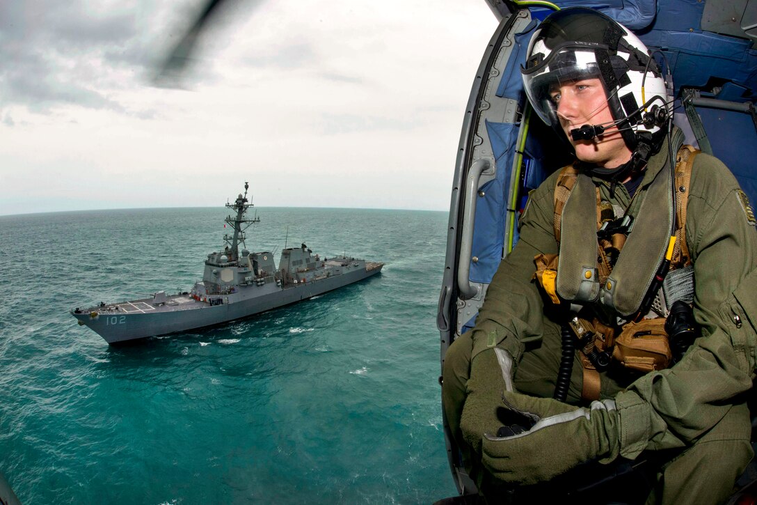 U.S. Navy Petty Officer 2nd Class Cody Witherspoon looks for debris as his helicopter returns to the guided missile destroyer USS Sampson as it supports Indonesian-led search efforts for AirAsia Flight 8501 in the Java Sea, Jan. 6, 2015. Witherspoon is a naval aircrewman assigned to Helicopter Maritime Strike Squadron 35. 