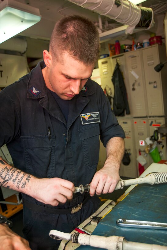 U.S. Navy Petty Officer 3rd Class Luke Winterfeldt disassembles landing gear connecting rings aboard the aircraft carrier USS Carl Vinson in the U.S. 5th Fleet area of responsibility, Jan. 6, 2015. Winterfeldt is an aviation structural mechanic.