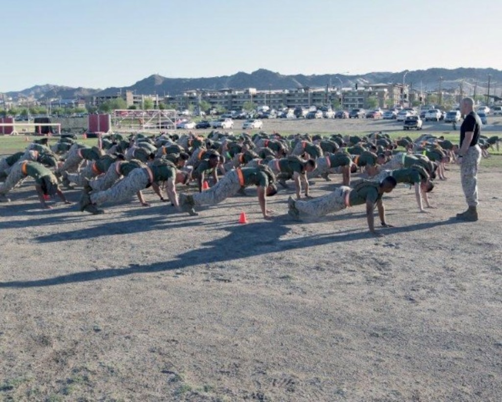 The Marines of Headquarters Company conduct warm-up exercises prior to Company High Intensity Tactical Training (HITT). Around once a month, all of Headquarters Company gets together to physically train in order to maintain Marine Corps Standards and boost morale. In events like the one shown, Marines complete physically demanding tasks as a team. 