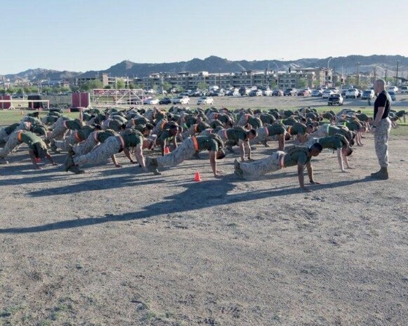 The Marines of Headquarters Company conduct warm-up exercises prior to Company High Intensity Tactical Training (HITT). Around once a month, all of Headquarters Company gets together to physically train in order to maintain Marine Corps Standards and boost morale. In events like the one shown, Marines complete physically demanding tasks as a team. 